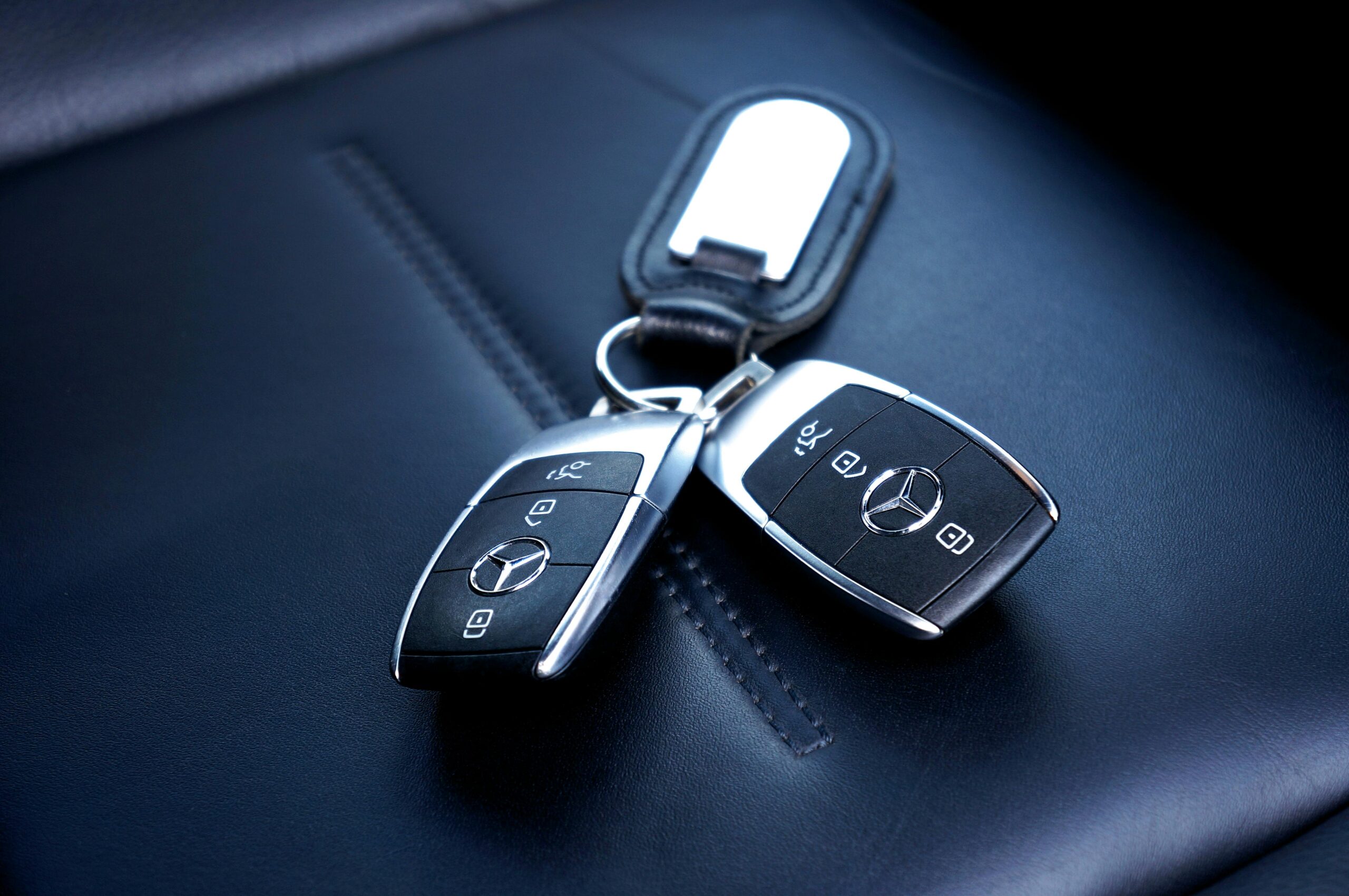 Two Mercedes Benz car keys resting on a luxurious leather seat, showcasing elegance and design.